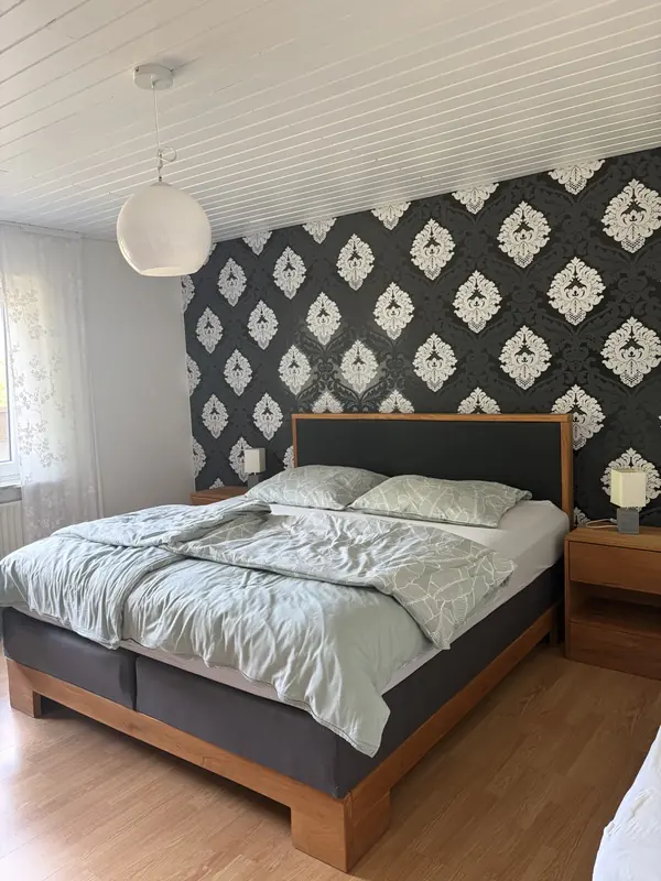 Schlafzimmer mit großem Boxspringbett vor gemusterter Akzentwand