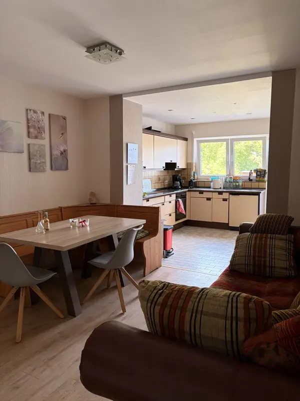 Offener Wohn- und Essbereich mit Sofa, Esstisch und Blick in die Küche